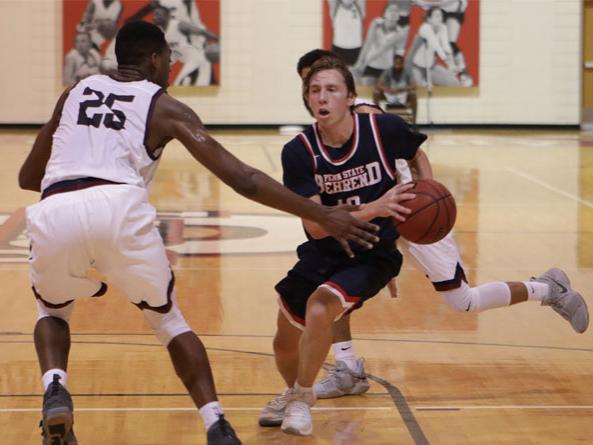 Penn State Behrend basketball player Andy Niland dribbles toward the hoop.