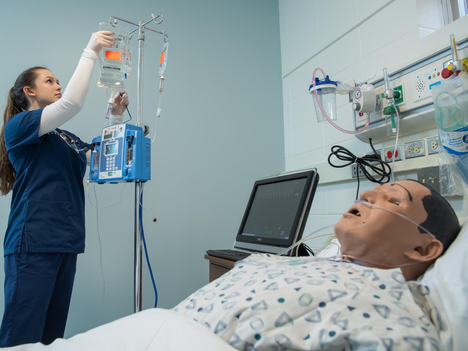 A nursing student prepares an IV in Penn State Behrend's nursing simulation lab