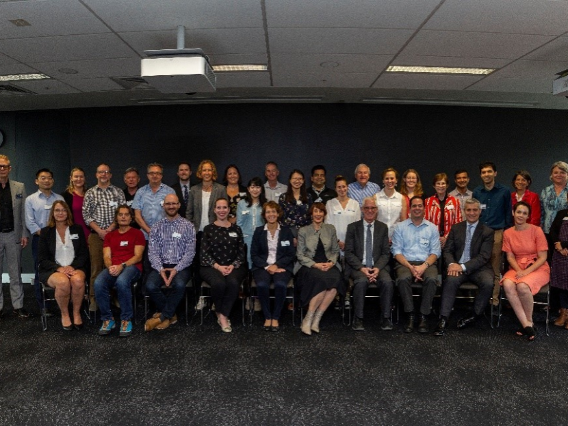 A large group of people (researchers, academics, and staff) sitting in rows in a large room