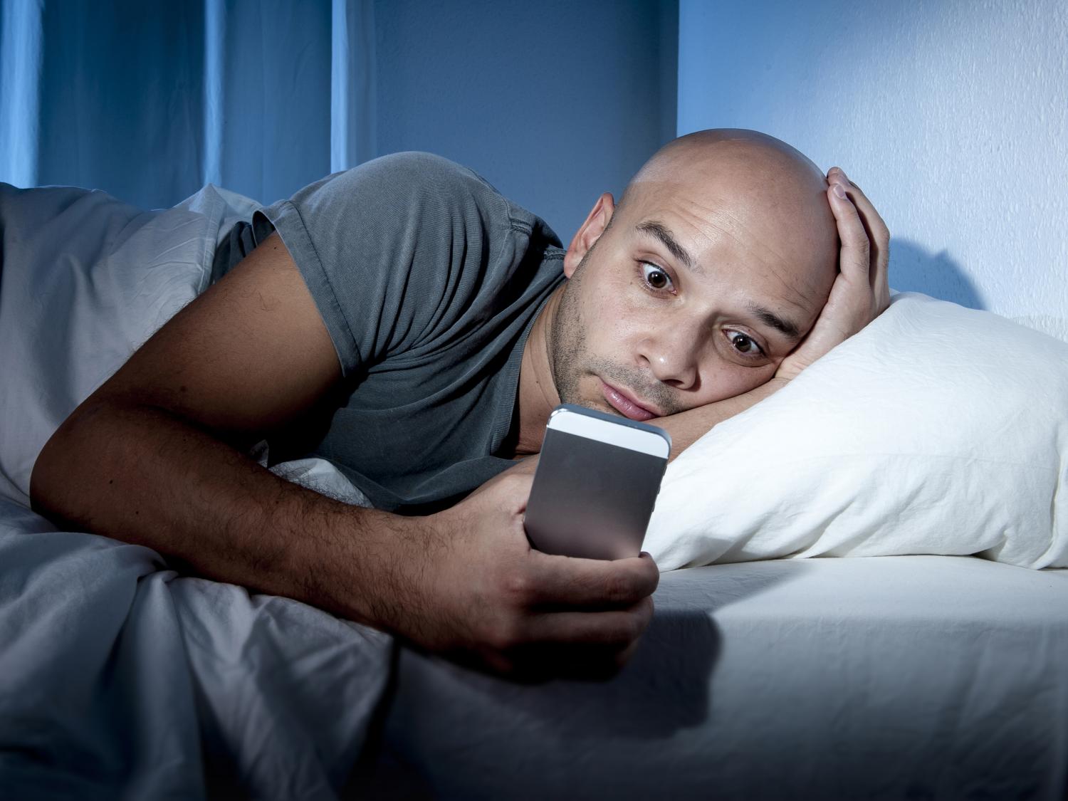 Man awake in bed with cell phone