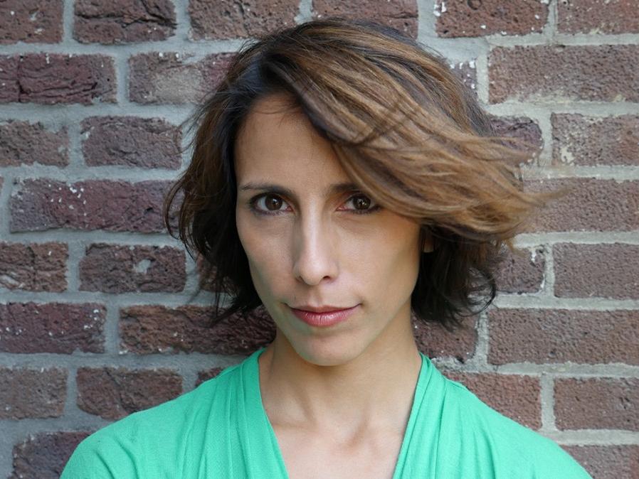 A woman shown from the shoulders up looks at the camera