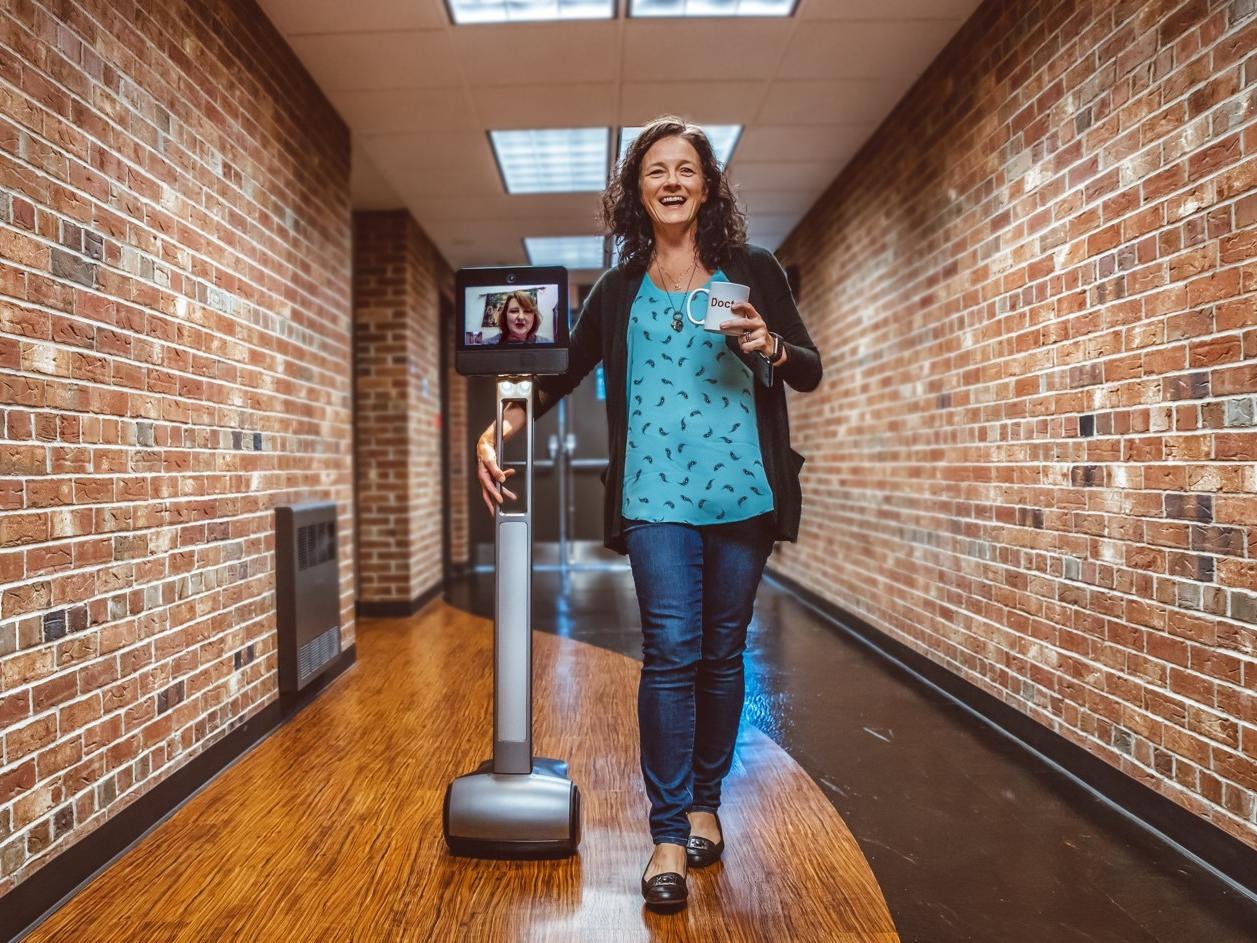 Penelope Morrison walks down a hall with Kristal Tucker projecting herself through the Beam robot