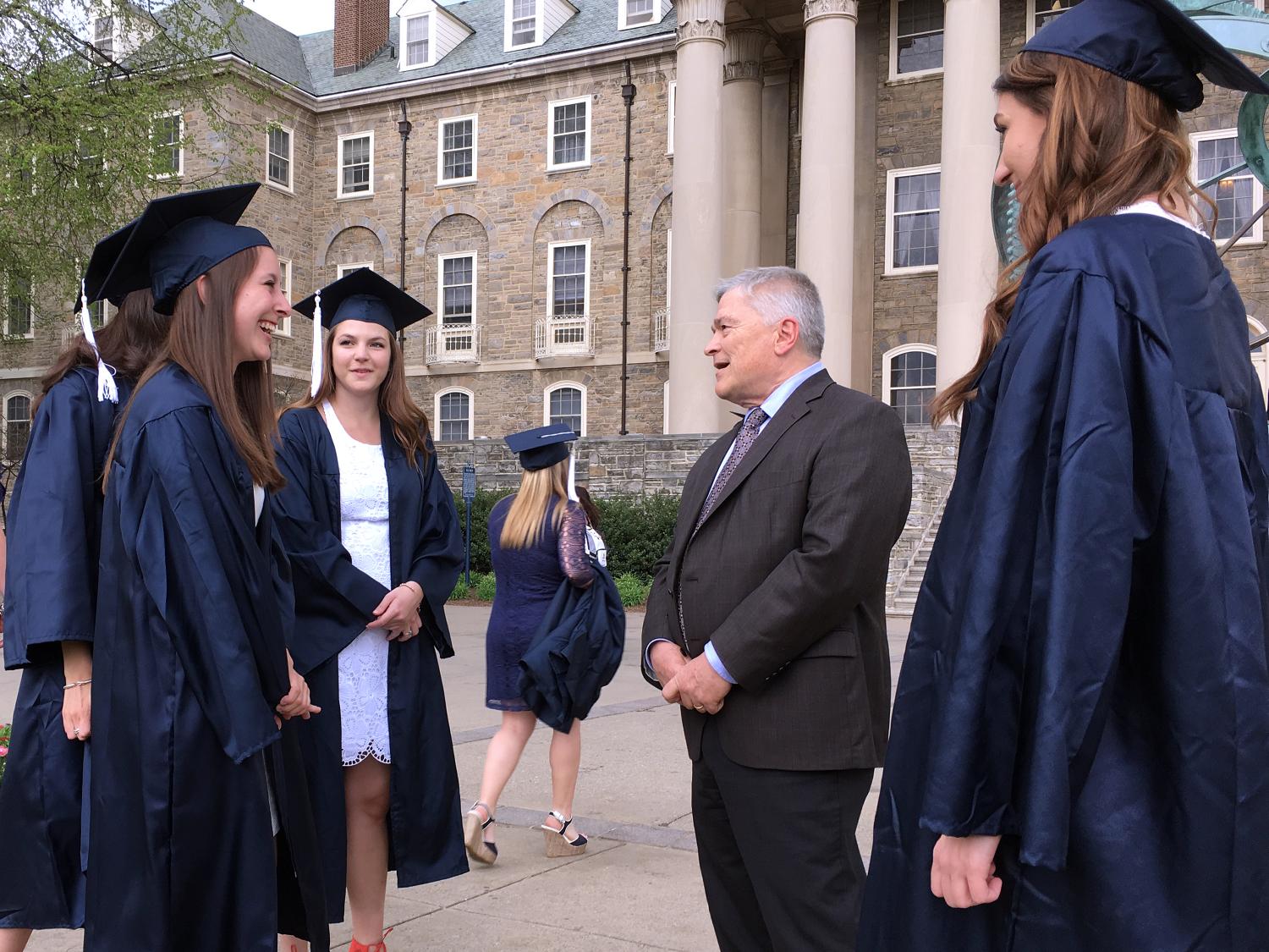 Penn State President Eric Barron stops by to speak with students as they take photos of themselves in their commencement robes in front of Old Main on April 22, 2016.
