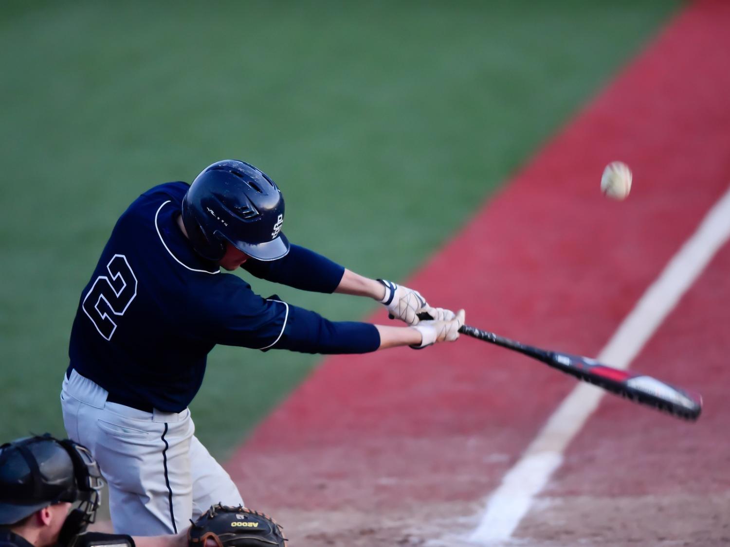 A Penn State Behrend baseball player hits the ball.