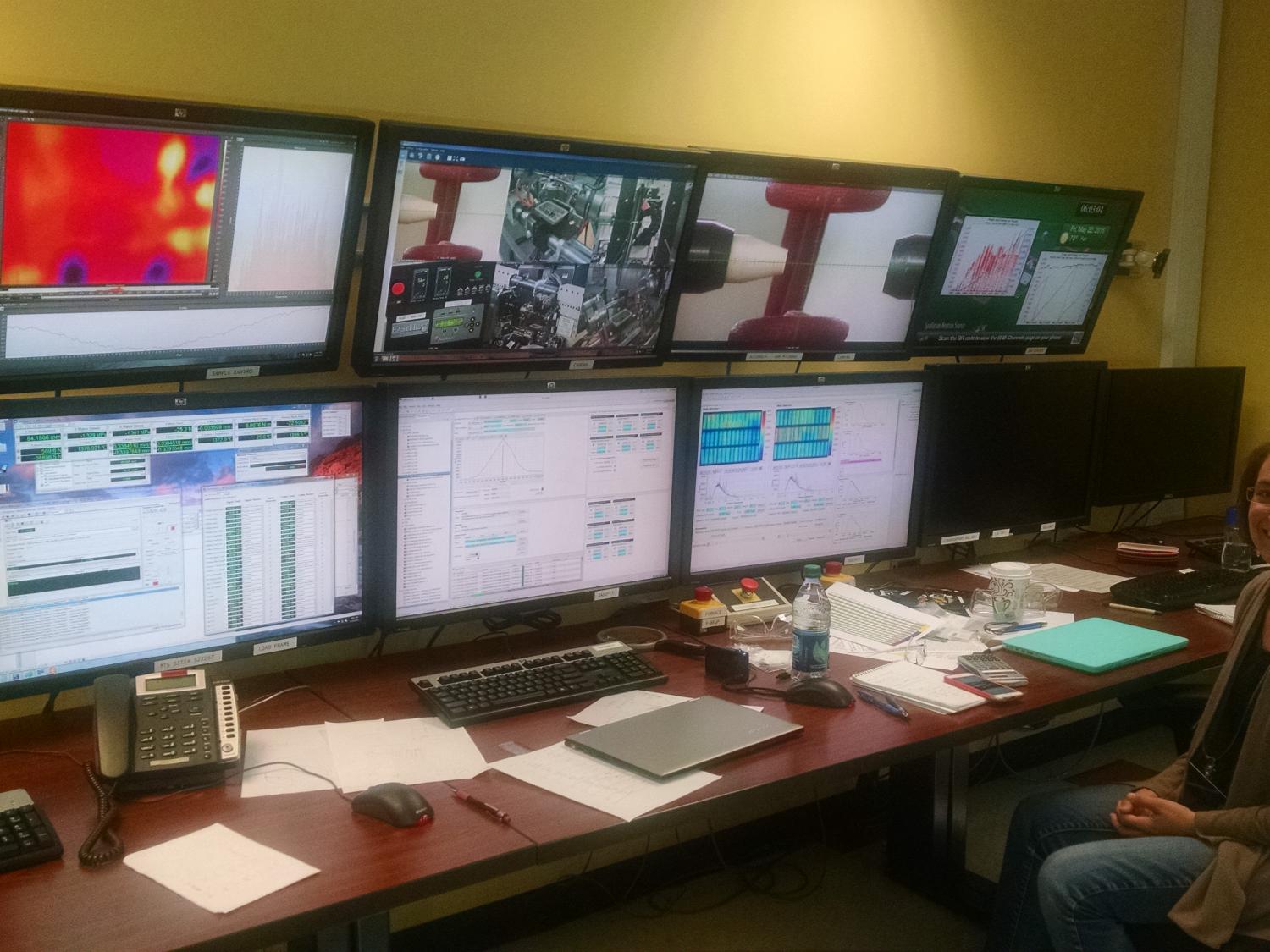 Allison Beese stand in front of a bank of monitors
