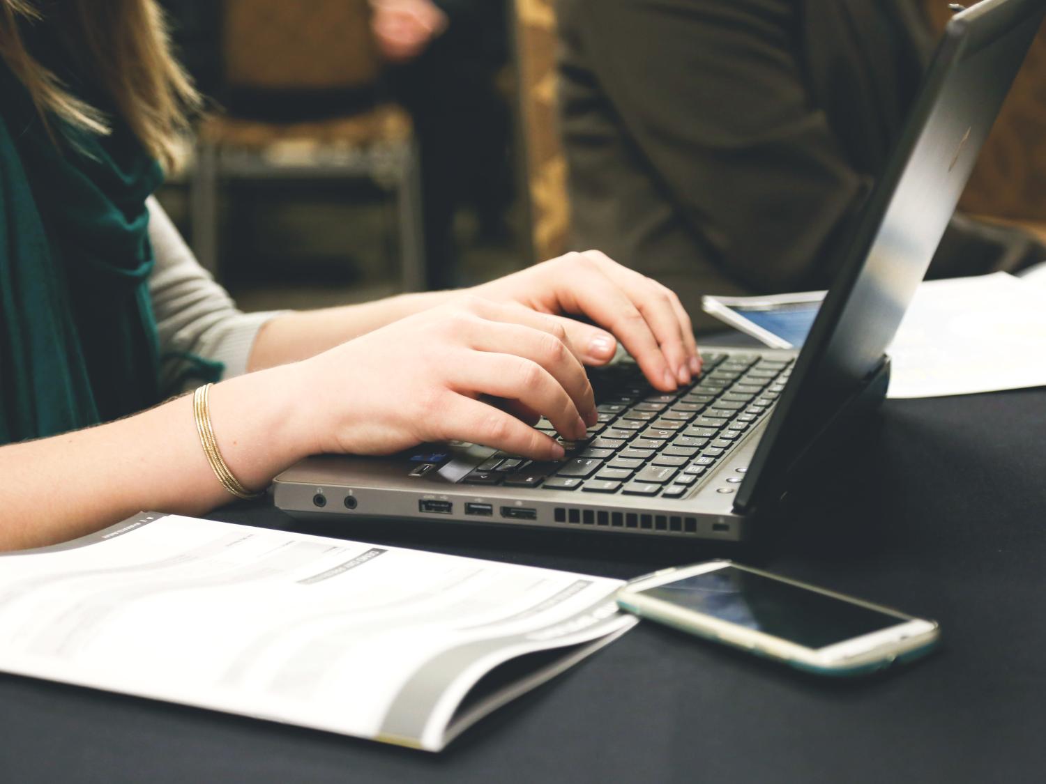 A close-up photo of a woman typing on a computer