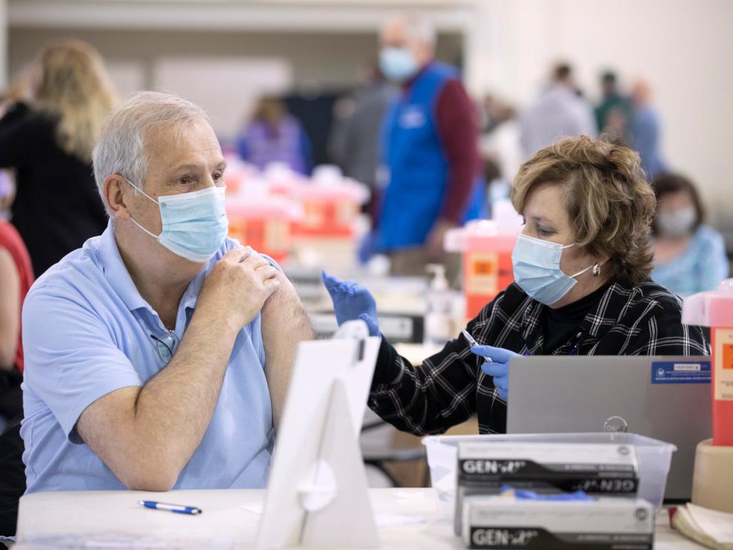 A nurse gives a man a vaccine in his arm