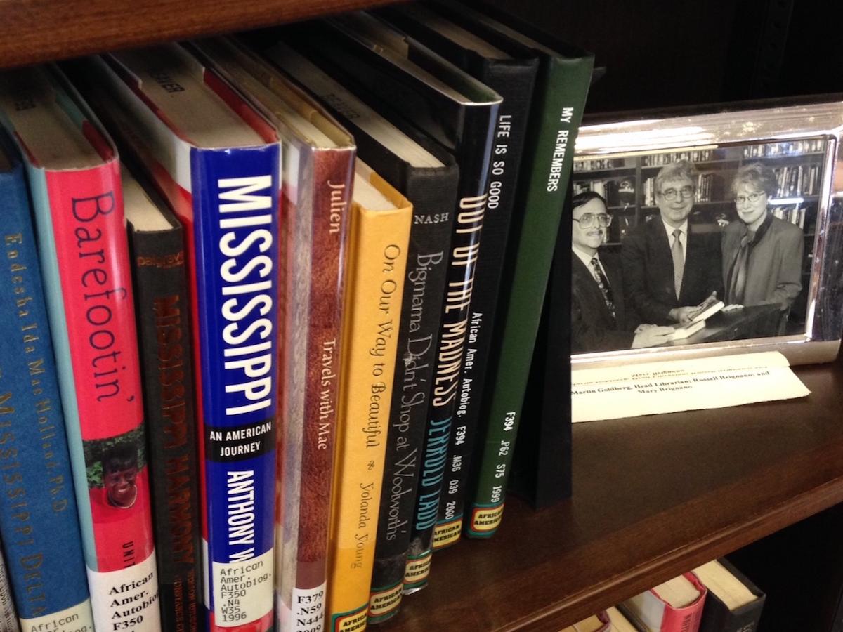 A photo of Russ Brignano sits beside books on a shelf.