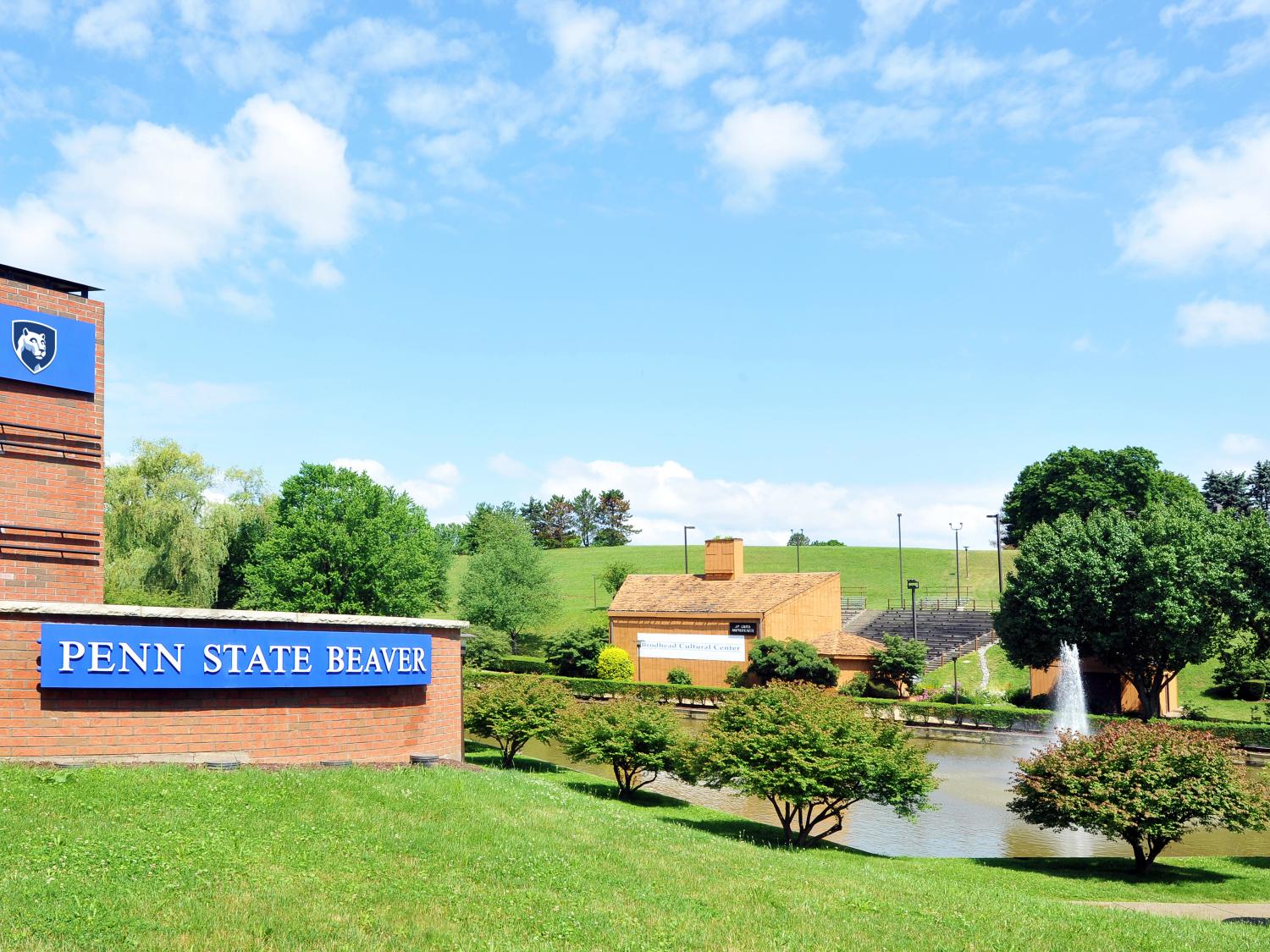 Campus entrance sign with pond and amphitheater in background.
