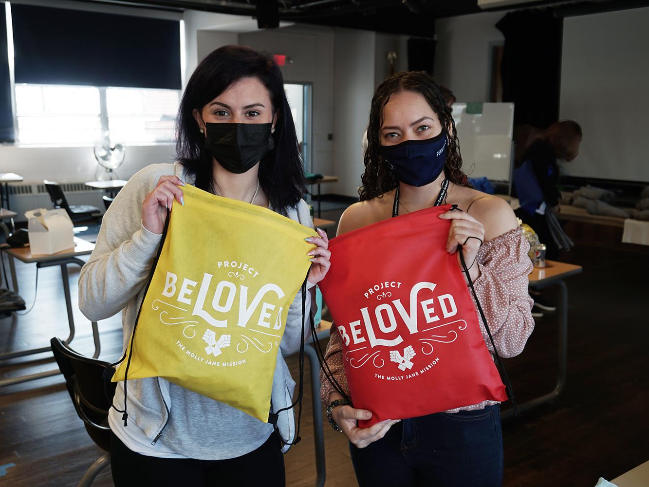Students holding draw-string bags with "Beloved" written on them.