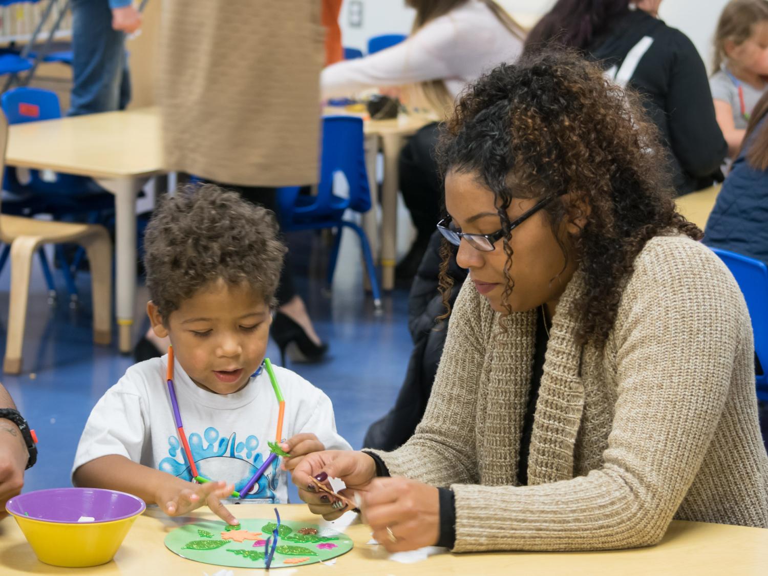 A woman and a boy work on a craft together at Penn College