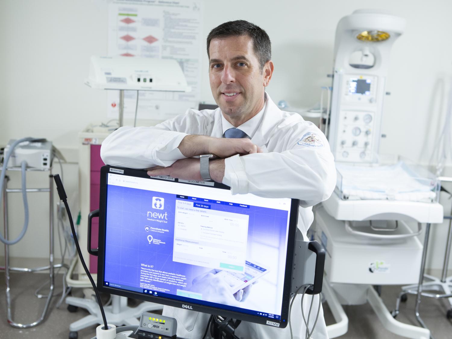 Dr. Ian Paul leans on crossed arms atop a computer monitor in a clinical room.