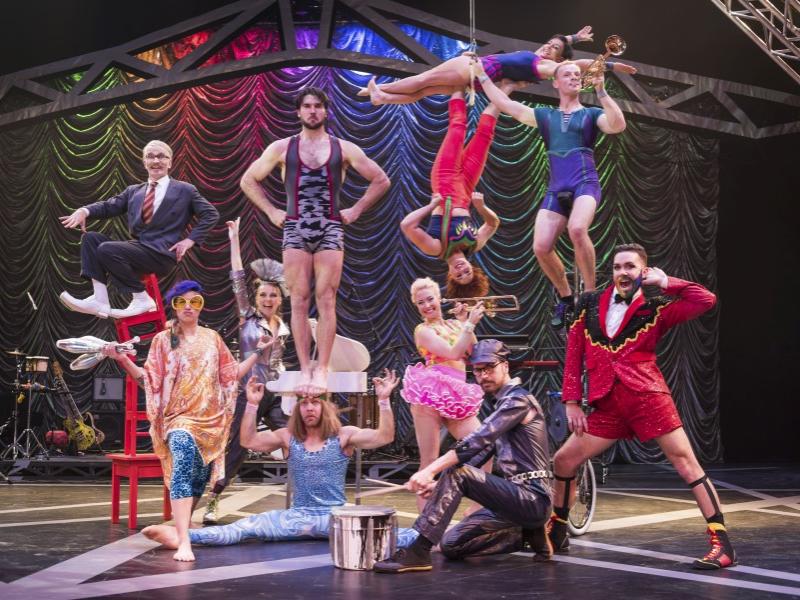 Members of the diverse Circus Oz troupe stand and kneel in various positions while looking at the camera.