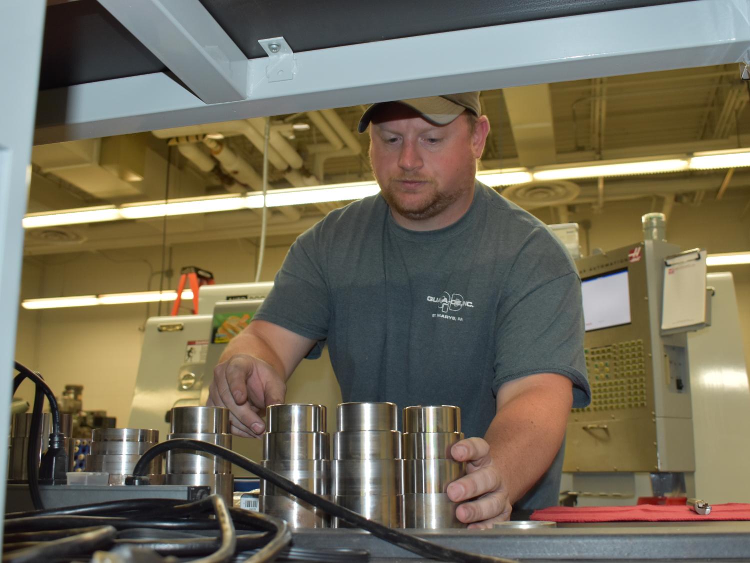 Instructor Curt Beck pulls newly created parts off of a CNC machine in the Penn State DuBois engineering labs.  