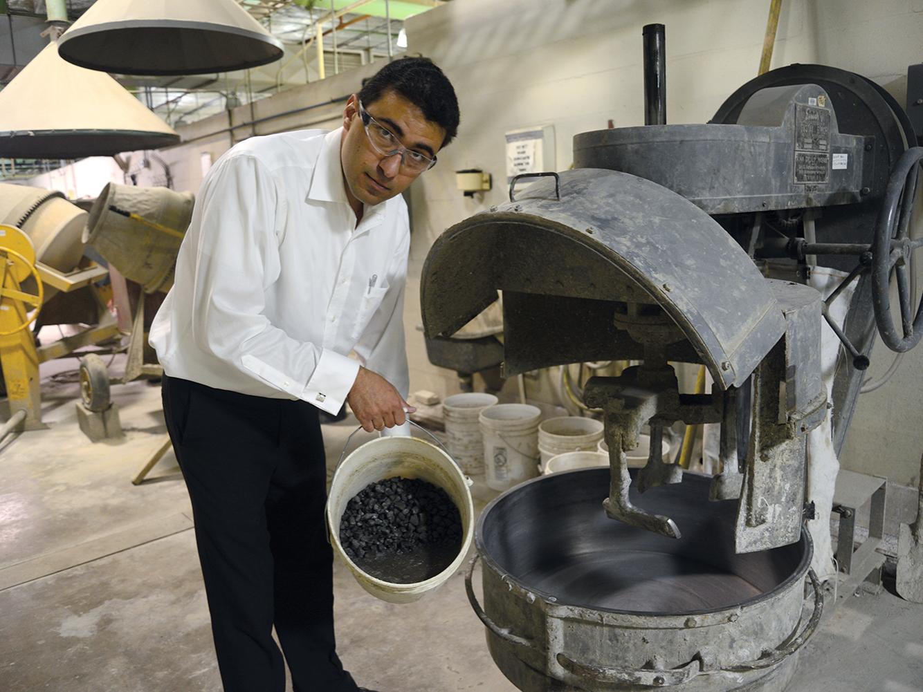 Farshad Rajabipour prepares to add aggregate to a concrete mixer.
