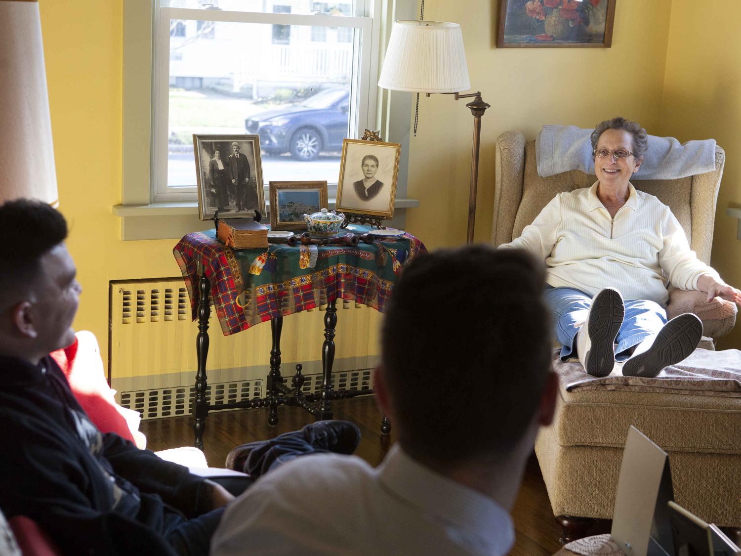 Medical students Matthew Chapman, left, and Yuriy Pechenyy sit on a couch and talk to Maria English, a longtime participant in the Patients as Teachers program. 