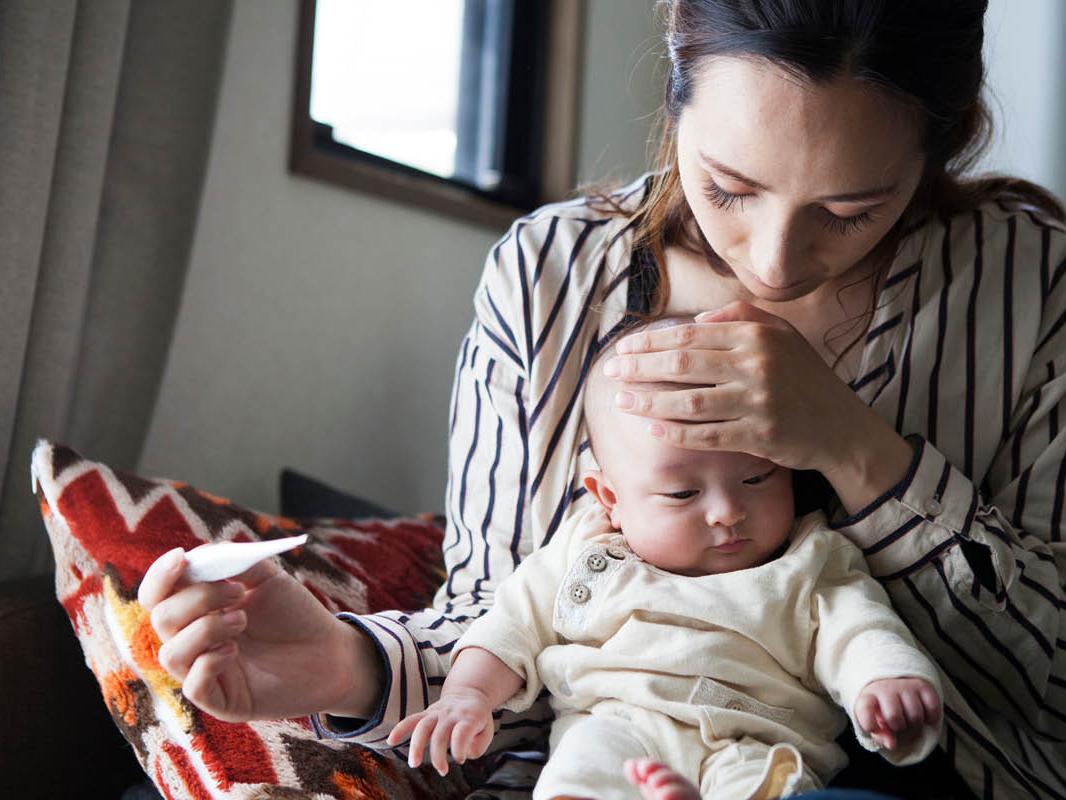 A mother takes the temperature of her baby