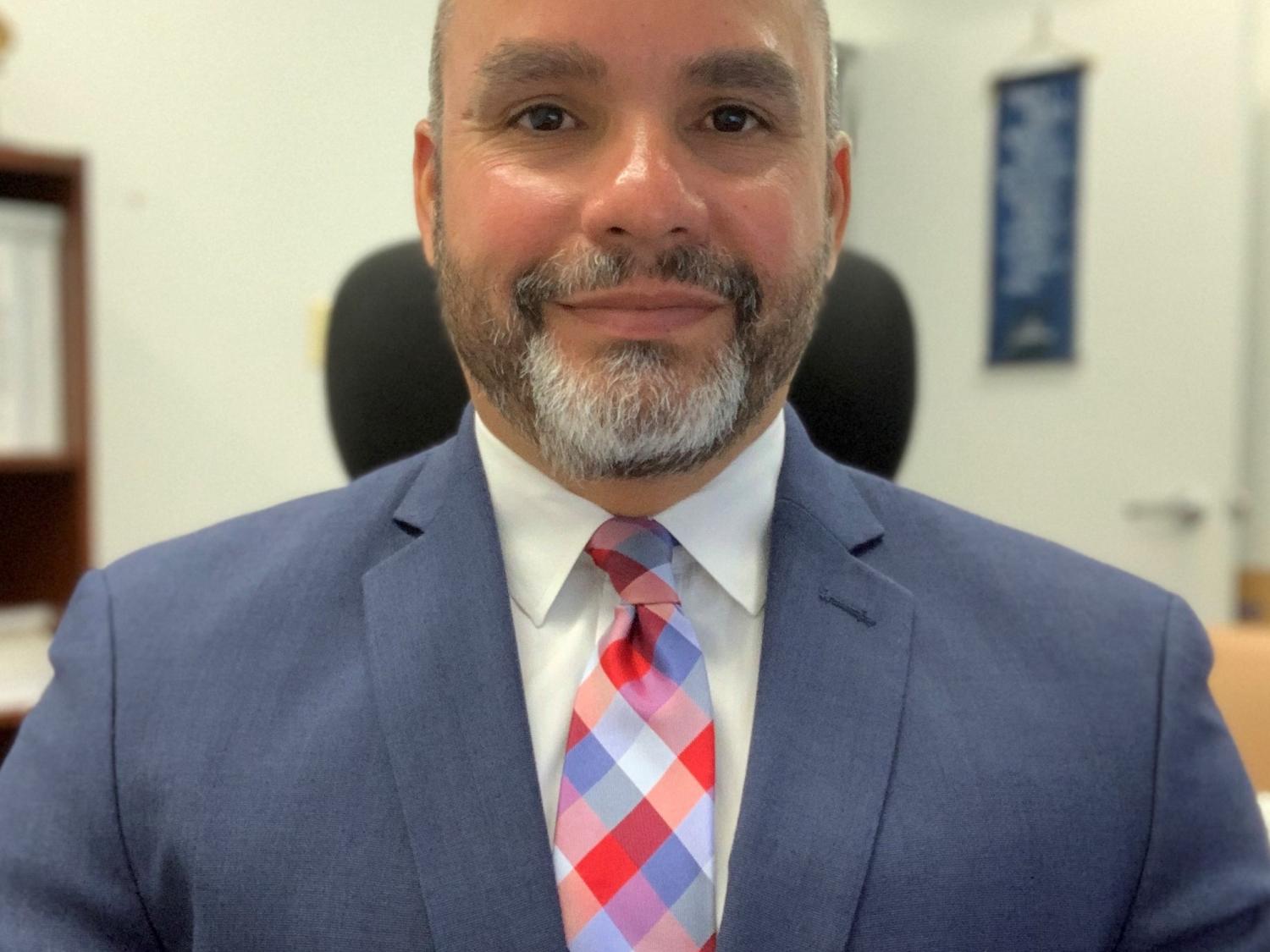 Man smiles in suit and tie for headshot.