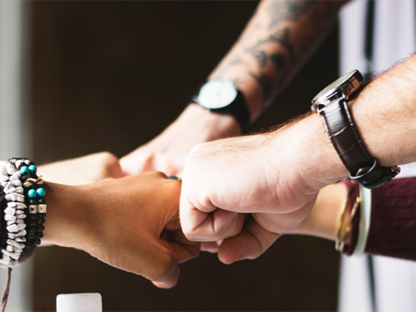 A group of fisted hands joining together.