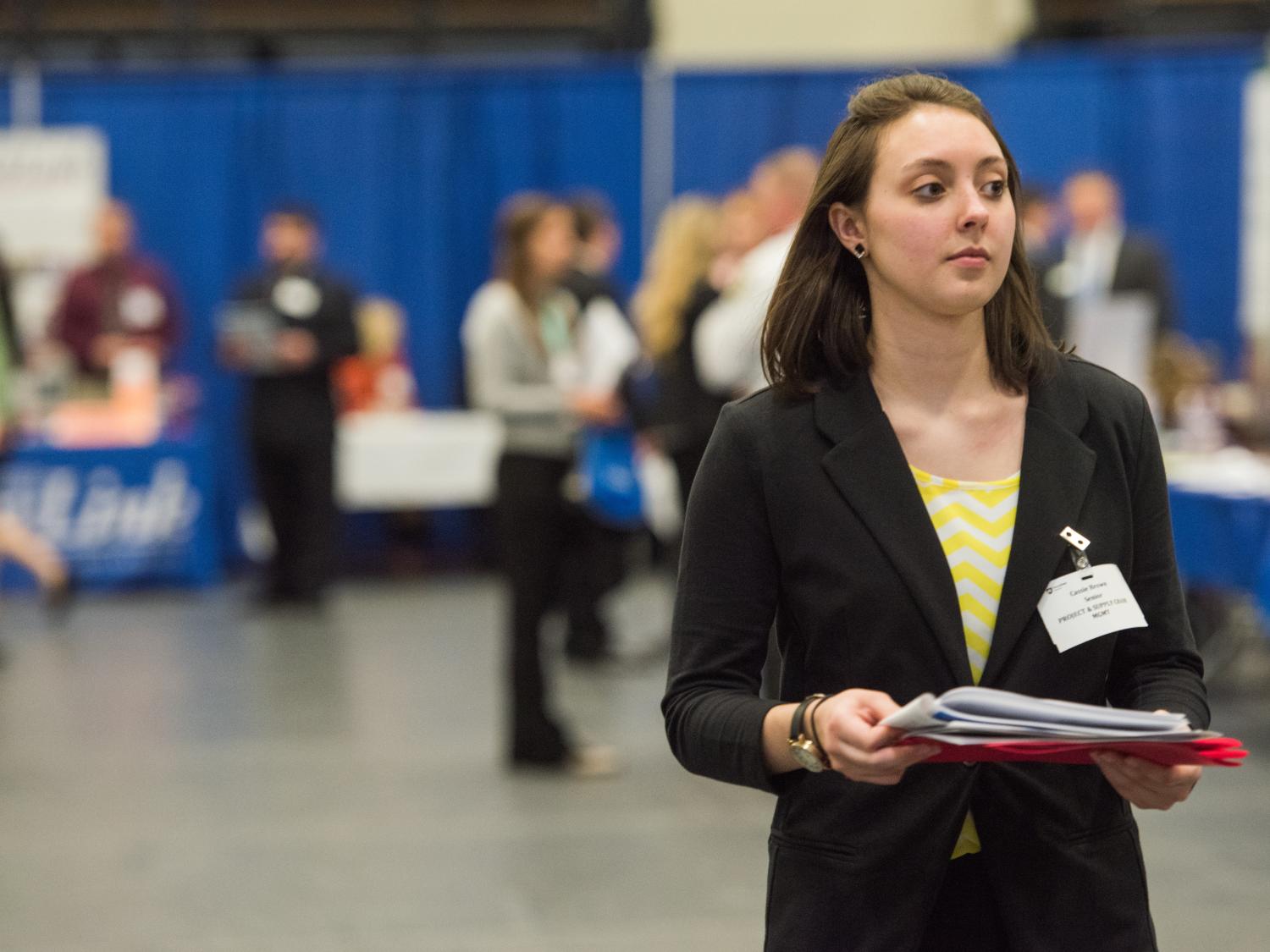 A female student walks down an aisle at a Penn State Behrend Career and Internship Fair