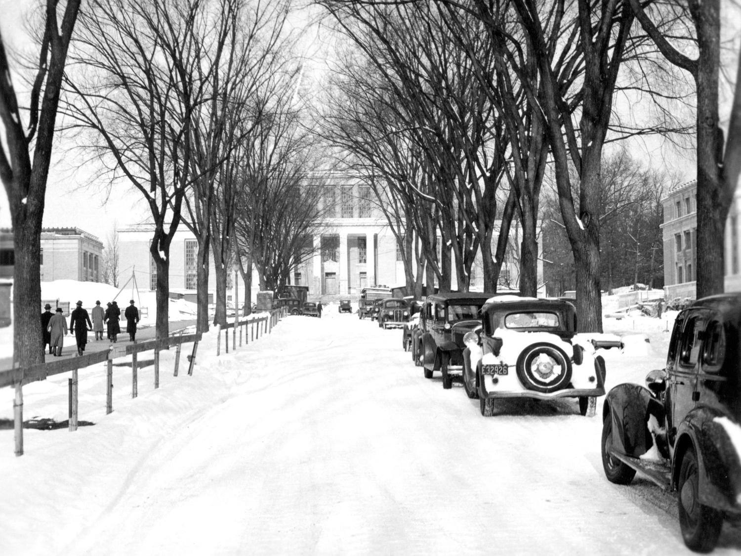 Cars parked on snowy road in front of Pattee Library, circa 1940