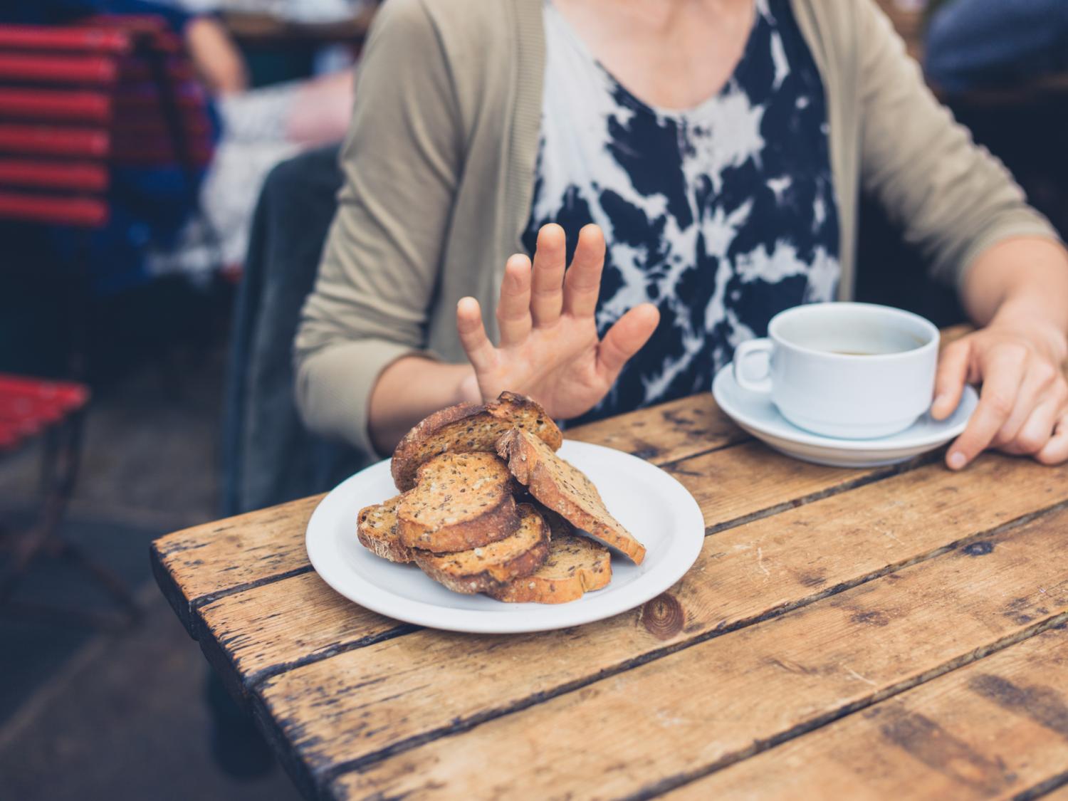 Woman on gluten free diet is saying no thanks to toast in a café.