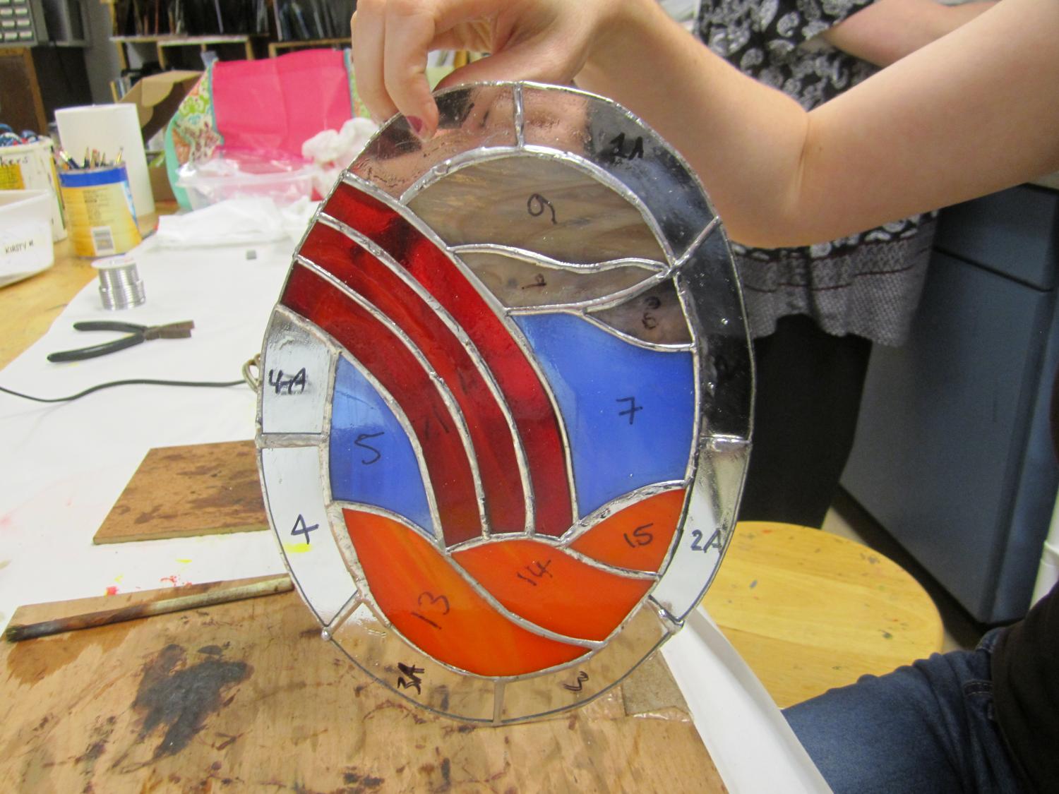 student holding up a stained glass project