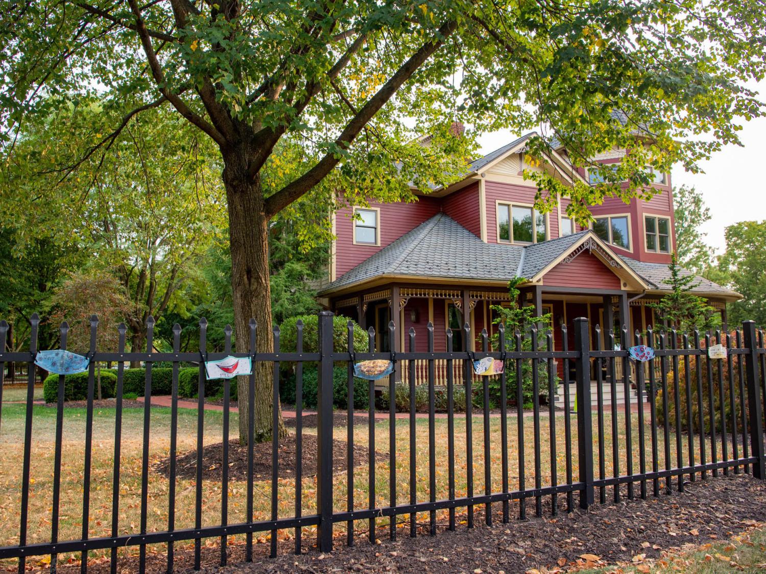 A victorian house with ceramic masks displayed on a fence in front of it