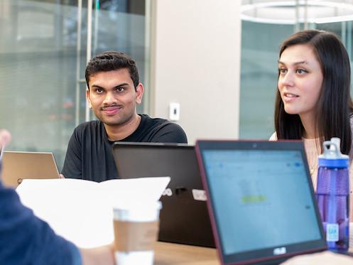 Man and woman discussing a project with laptop in foreground.