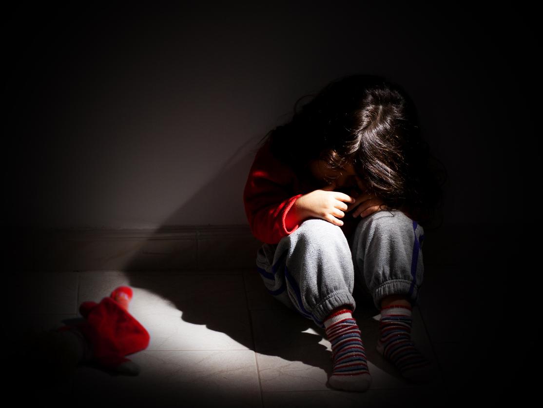 Dark, child huddled on floor