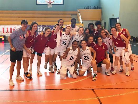 A group photo of women basketball players standing together on an indoor basketball court