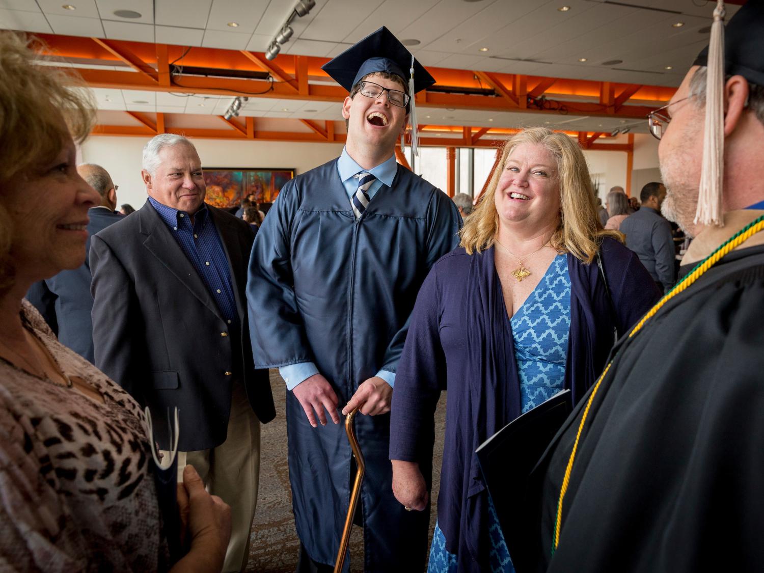 a graduate smiling with his parents