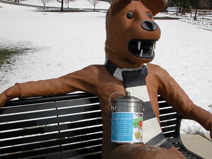 The Nittany Lion statue with a compost container.
