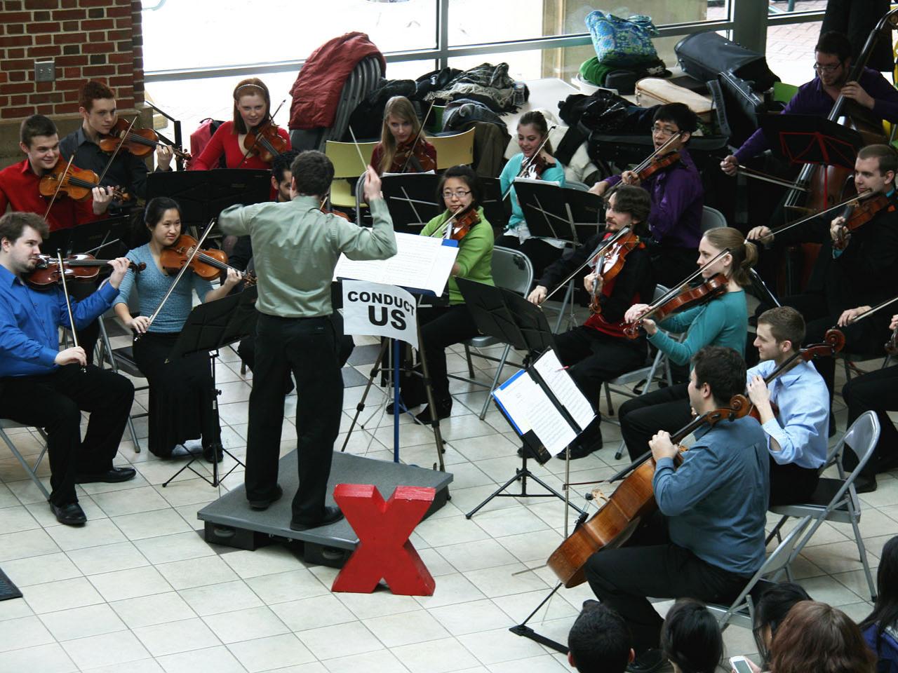 student volunteer conducts small orchestra