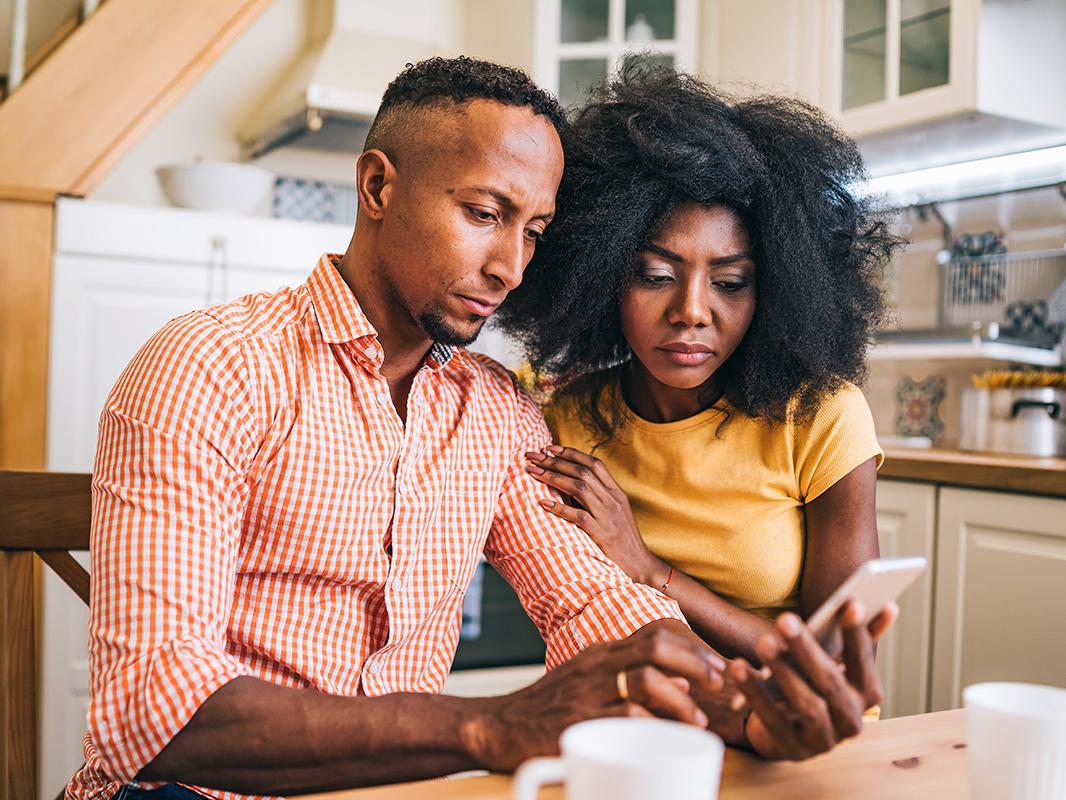 A couple looks worried while reading information on a phone. 