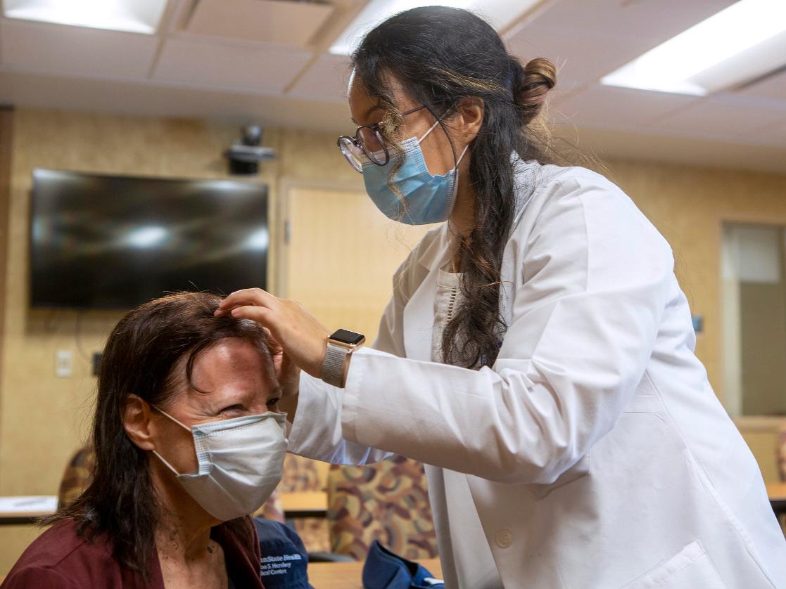 A doctor looks at the top of a patient's head