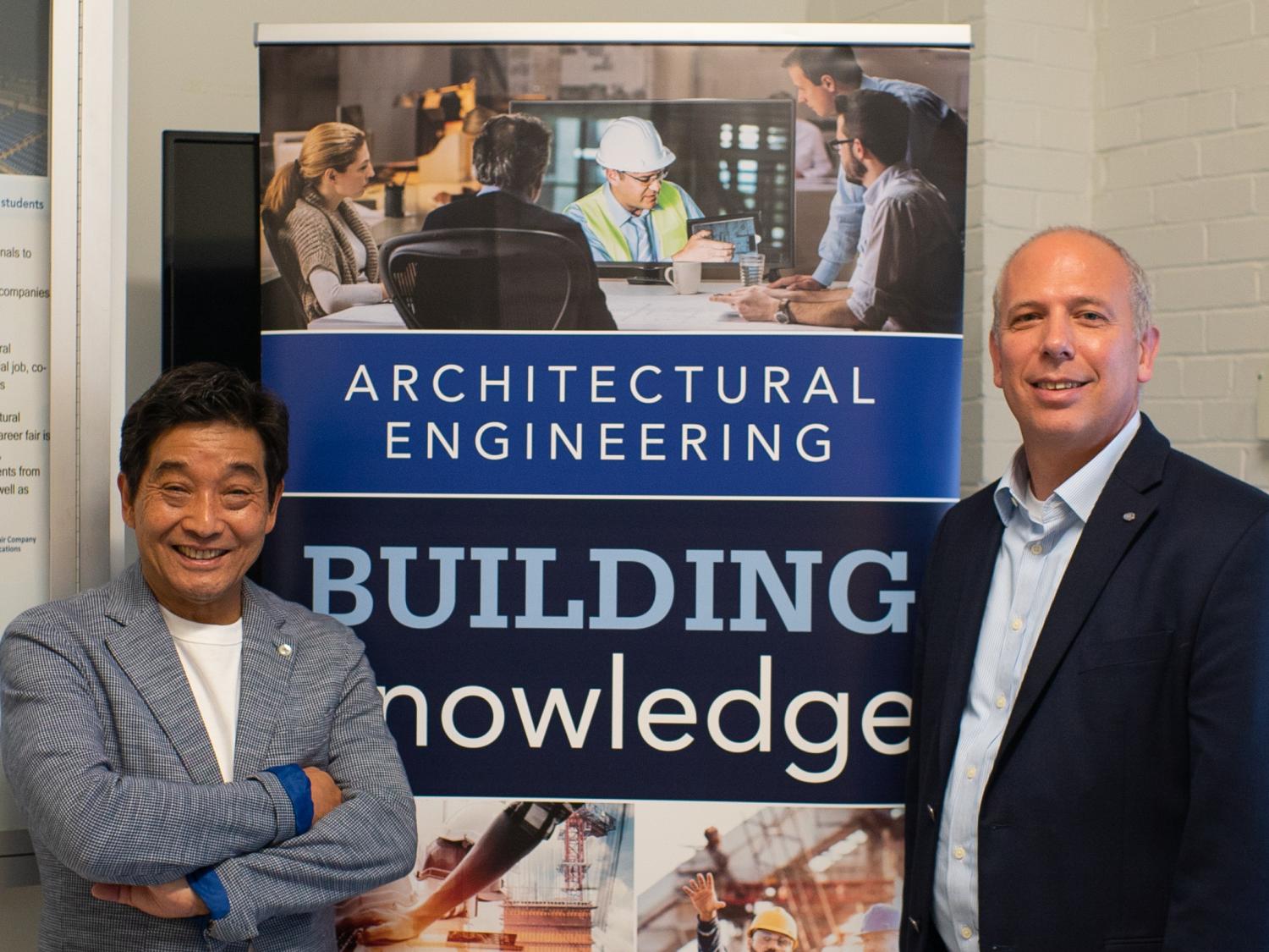 Kenichi Kawamura of Fujita and John Messner, professor of Architectural Engineering standing in front of an AE sign
