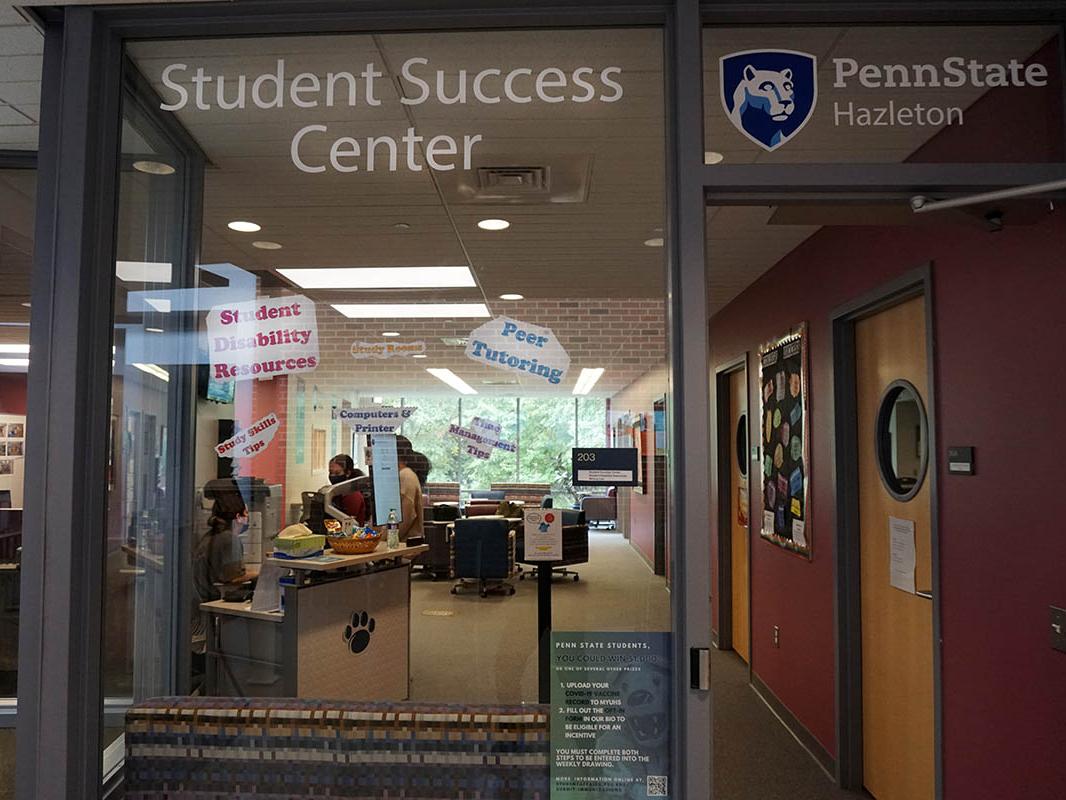Glass window looking into room with students gathered around a desk.