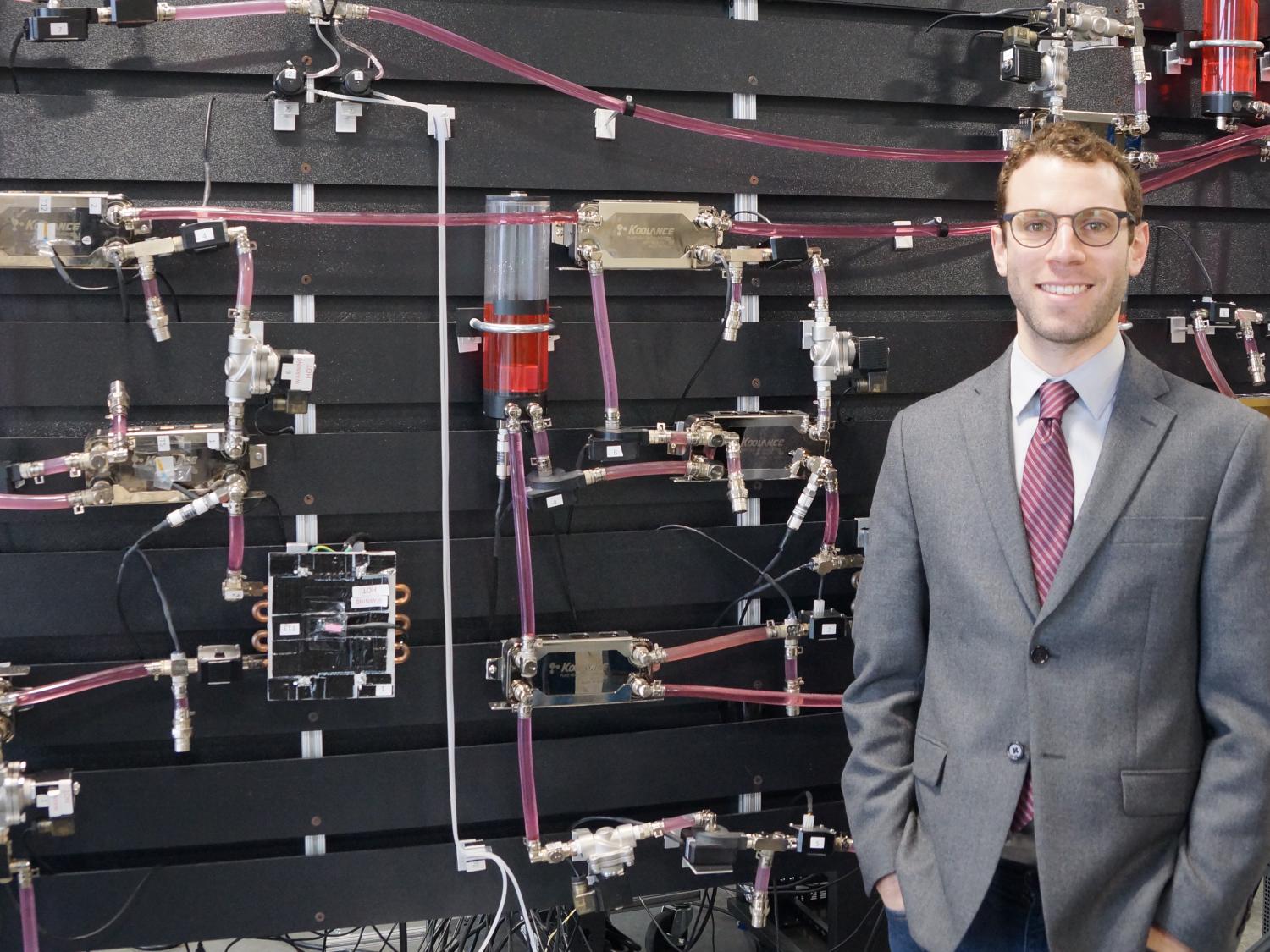 Man standing in front of a wall of machinery. 