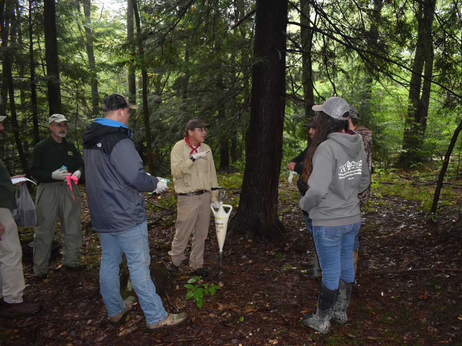 DCNR Forester Bill Laubscher, center, demonstrates the application of insecticide around the base of hemlock trees. 