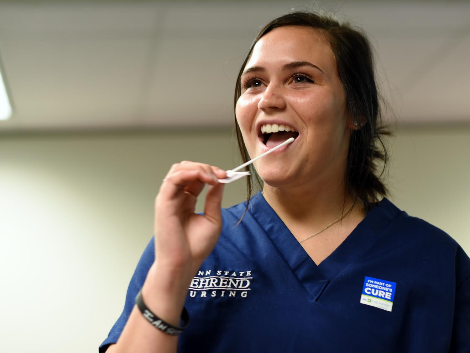 A Penn State Behrend student swabs her cheek for a DNA sample.