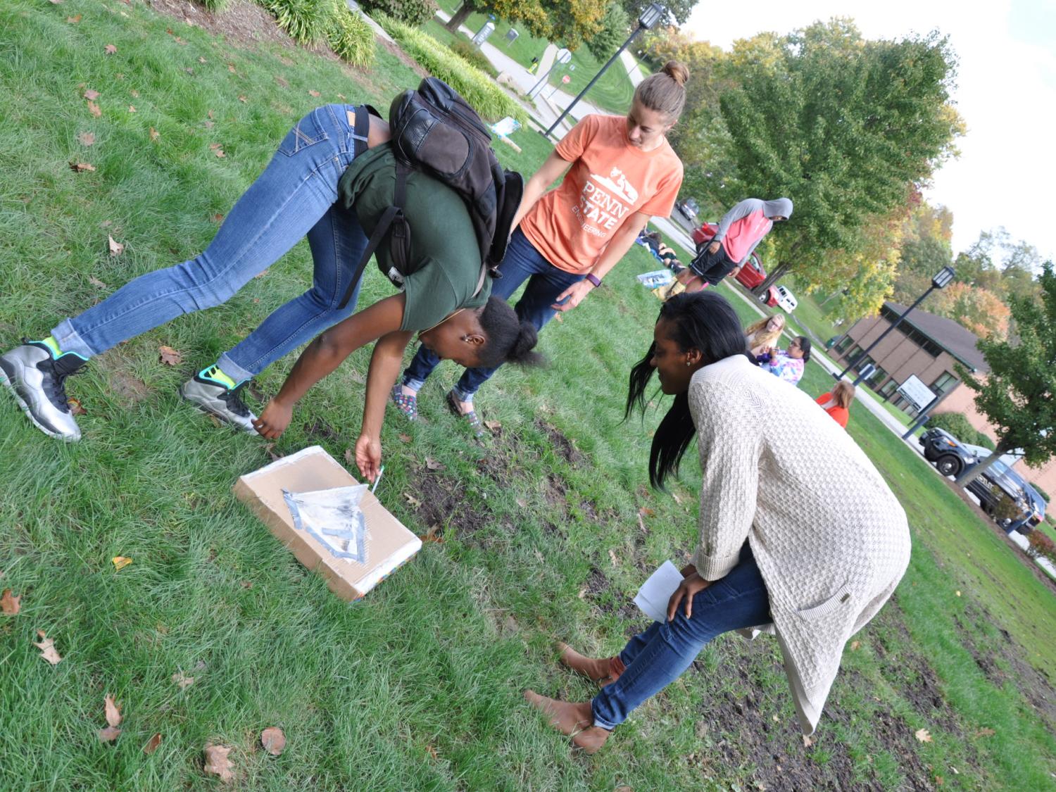 students bending over on lawn