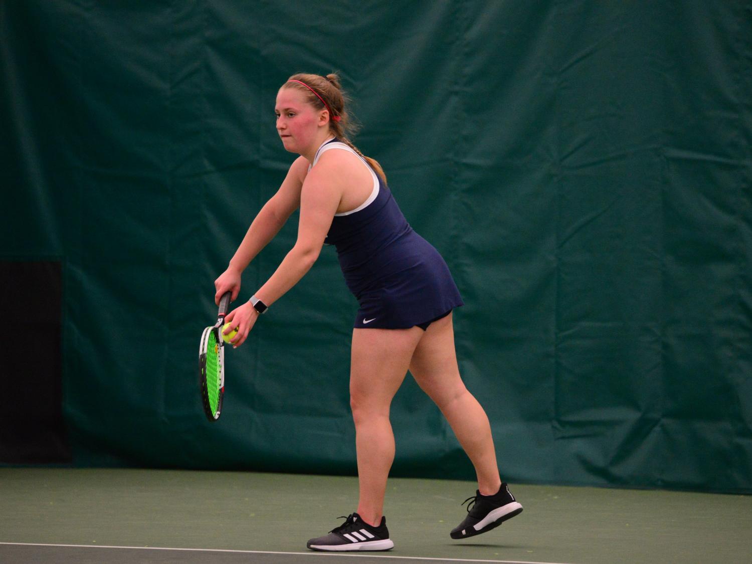 A Penn State Behrend tennis player prepares to serve.