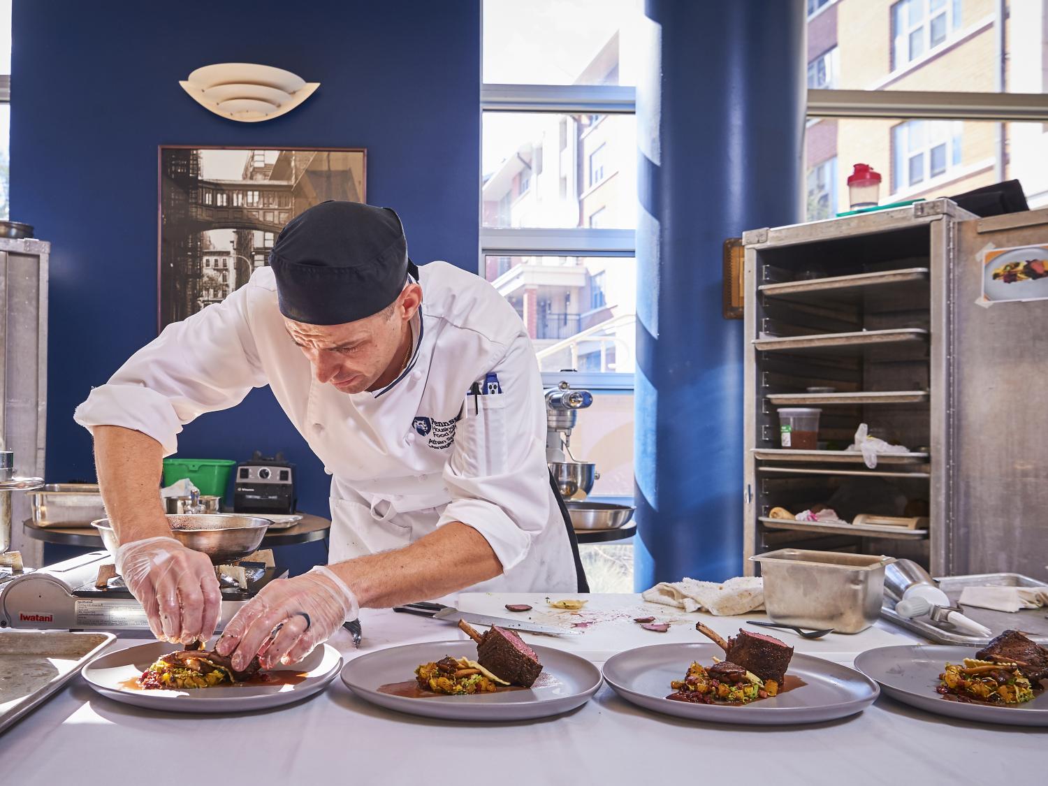 A chef works on plating food