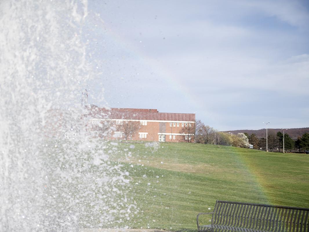 The Penn State Fayette fountain appears behind a rainbow