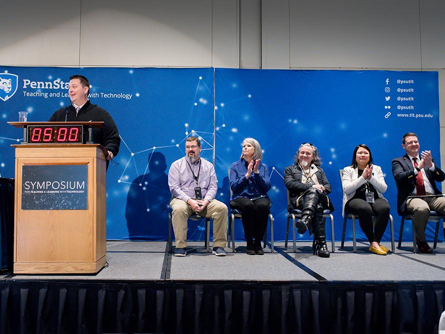 Five Open Innovation Challenge finalists are seated on stage as they wait to present their ideas