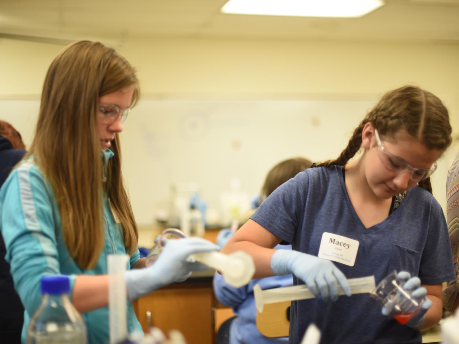 Abbey Frederick and Macey Eyler pour DNA into beakers.