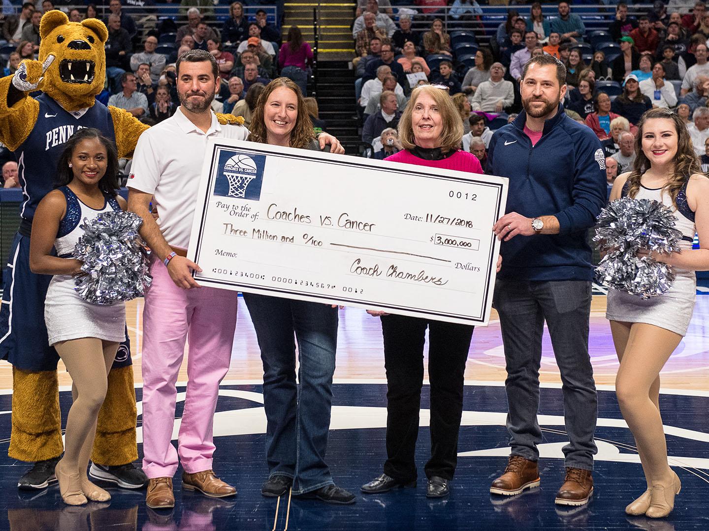 Group holds large check at half court