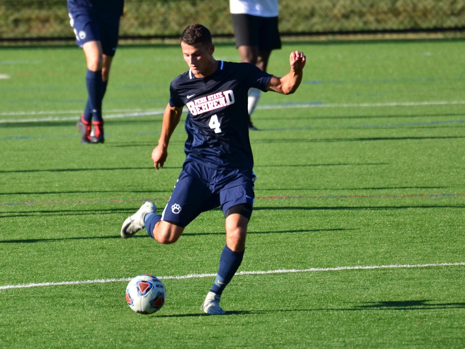 A Penn State Behrend soccer player kicks the ball up the field.