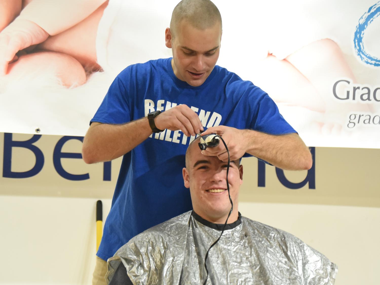 A Penn State Behrnd baseball player shaves a teammates head during a fundraising event.